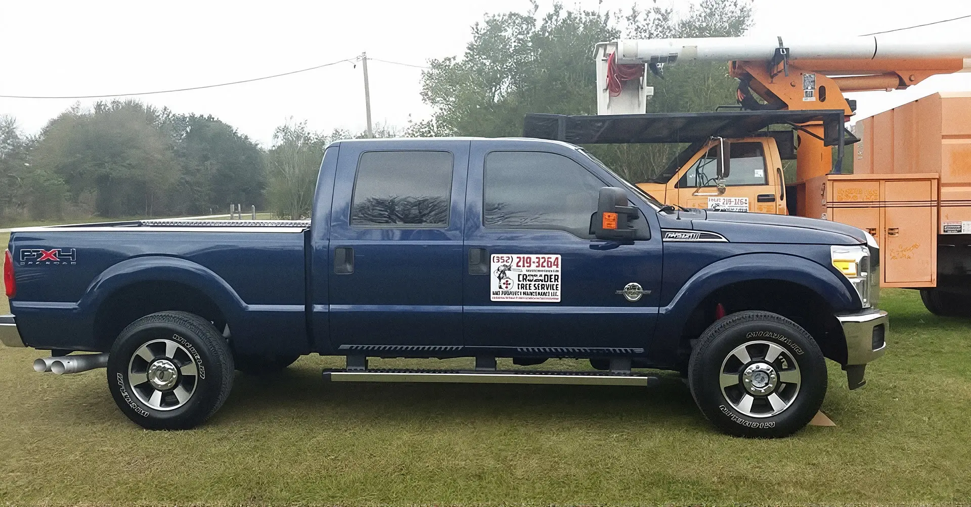 Crusader Tree Service pickup truck parked in front of a bucket truck